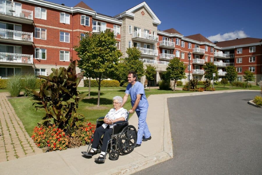 Care-Homes-1 Photo of a carer pushing a lady in a wheelchair